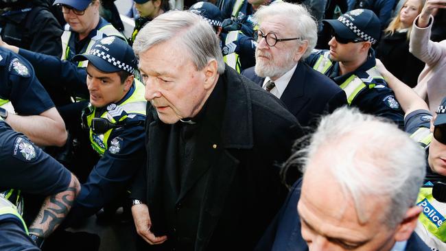 Cardinal Pell walks with a heavy Police outside court last year. Picture: Getty