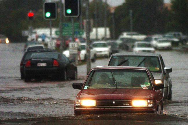 Gold Coast, June 30, 2005. Vehicles cross a flooded intersection at Varsity Lakes on Queensland’s Gold Coast today. Widespread flooding has hit the popular tourist area, known for its sunshine and sandy beaches, with reports of rainfall reaching 80mm per hour in some regions. (AAP Image/Tony Phillips)