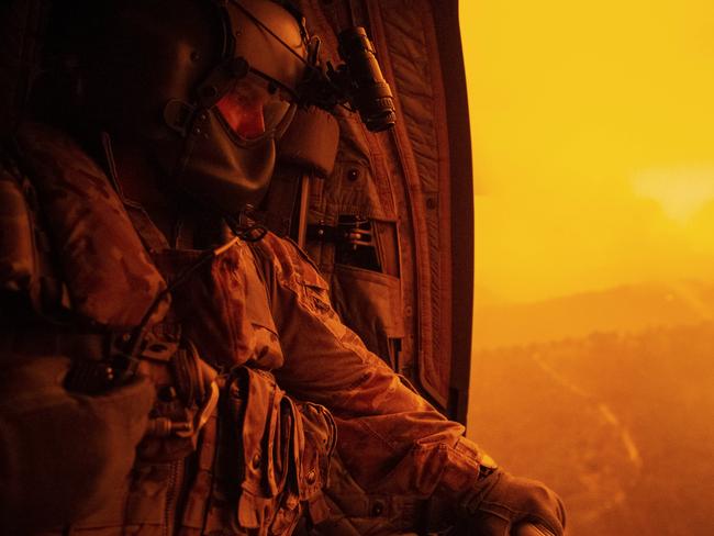 Warrant Officer Class Two Darrel Rowe, from the 5th Aviation Regiment, searches the ground from an Australian Army CH-47F Chinook during the flight to Omeo, Victoria to evacuate local civilian residents during Operation Bushfire Assist 19-20.