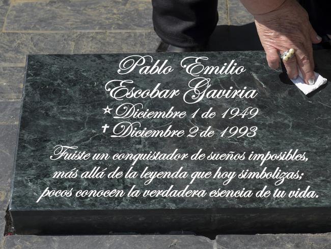 The sister of the Colombian drug lord Pablo Escobar, Luz Maria Escobar, cleans a plaque on his tomb, at the Montesacro cemetery in Medellin, Colombia. Picture: AFP