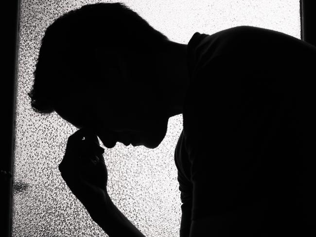 Young sad man sitting in the dark room.