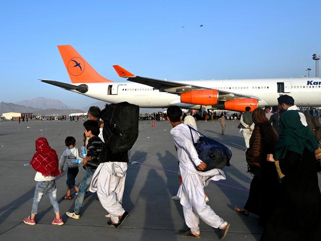 Afghan families walk by the aircrafts at the Kabul airport. Picture: AFP