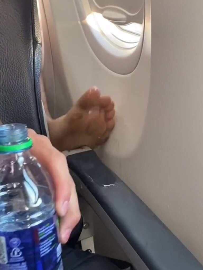 The video shows the passenger behind putting his feet on the arm rest