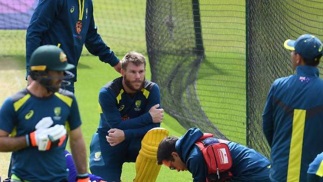 Australia's David Warner looks on as an injured net bowler receives medical attention during a training session at The Oval in London.