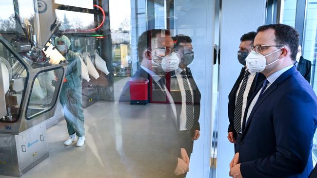 German Health Minister Jens Spahn looks at the vaccine bottling plant as he tours the lab facilities of vaccine maker IDT Biologika.