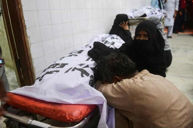 Relatives mourn beside a victim who died when a Ramadan alms distribution for people in need in Karachi sparked a stampede