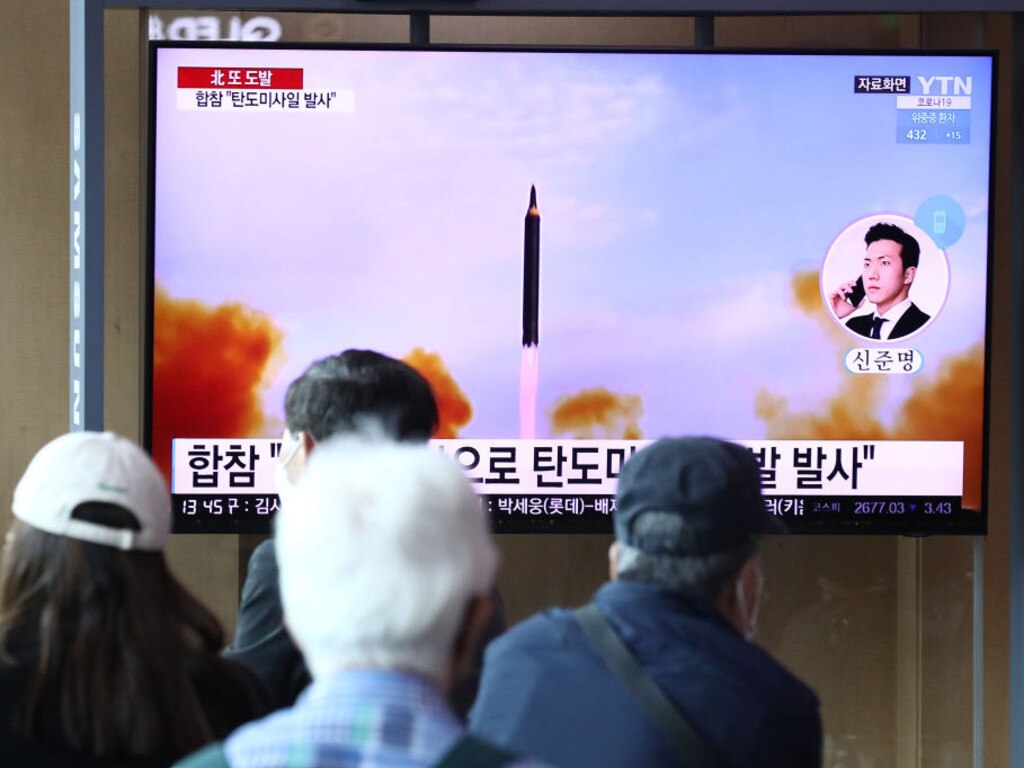 People watch a television broadcast showing a file image of a North Korean missile launch.