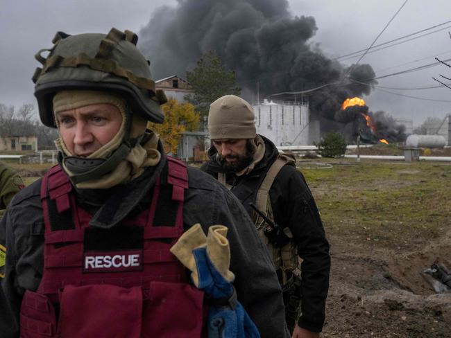 A Ukrainian rescue service member and a soldier inspect the area as black smoke rises from an oil reserve in Kherson. Picture: AFP