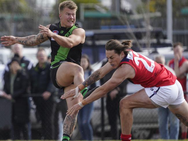 Doveton’s Trent Mcmahon gets a kick away as Chelsea Heights’ Aaron Rhodes tries to smother. Picture: Valeriu Campan