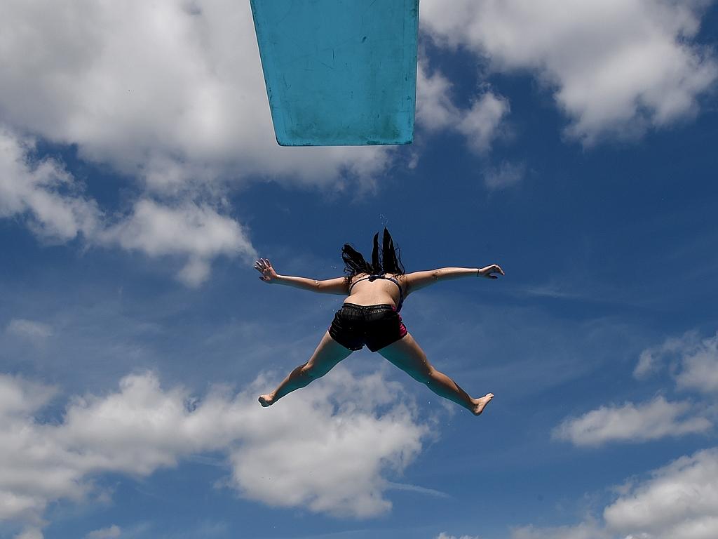 A woman jumps from a diving platform into the water of the public open-air swimming pool in Neumuenster, northern Germany, on June 30, 2015. Meteorologists forecast temperatures across the country of 30 degrees Celsius and even more. Picture: AFP