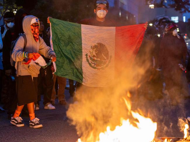 A protester holds the Mexican flag as demonstrators clash with law enforcement. Picture: RINGO CHIU / AFP