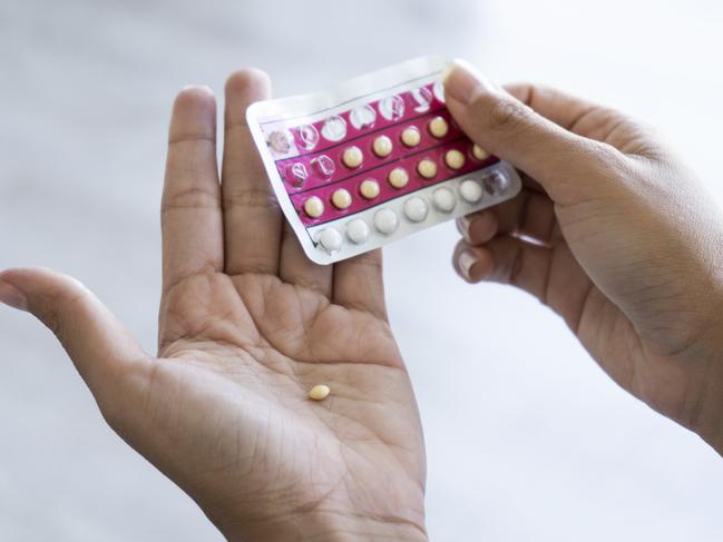 Close-up of young woman's hand holding birth control pills