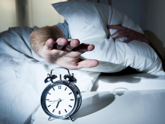 sleeping man disturbed by alarm clock early morning