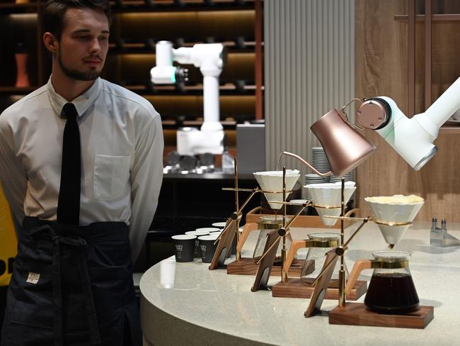 A man dressed in a barista's outfit watches as an LG CLOi CoBot Barista robot makes pour-over coffee, at the LG booth, 2020 Consumer Electronics Show. Picture: AFP