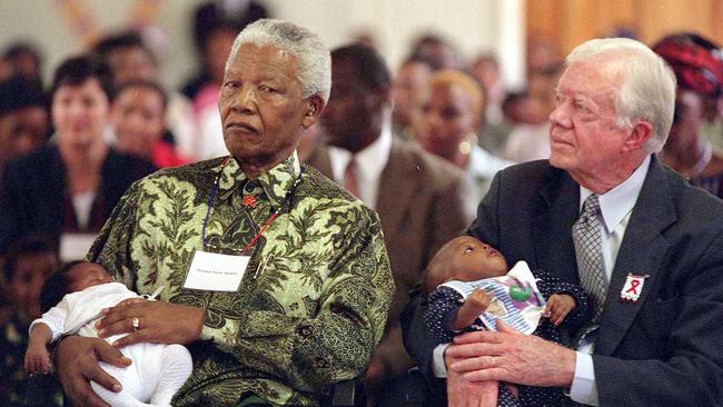 Mr Carter and Nelson Mandela hold HIV-positive babies at the Zola Clinic in Soweto, South Africa, in 2002. Picture: AP