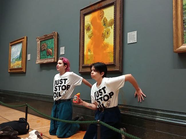 TOPSHOT - A handout picture from the Just Stop Oil climate campaign group shows activists with their hands glued to the wall under Vincent van Gogh's "Sunflowers" after throwing tomato soup on the painting at the National Gallery in central London on October 14, 2022. - London's Metropolitan Police said its officers arrested two protesters from the Just Stop Oil group for criminal damage and aggravated trespass after they "threw a substance over a painting" at the gallery on Trafalgar Square. (Photo by Handout / Just Stop Oil / AFP) / RESTRICTED TO EDITORIAL USE - MANDATORY CREDIT "AFP PHOTO / JUST STOP OIL " - NO MARKETING - NO ADVERTISING CAMPAIGNS - DISTRIBUTED AS A SERVICE TO CLIENTS