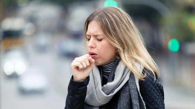 Shot of illness young woman coughing in the street.