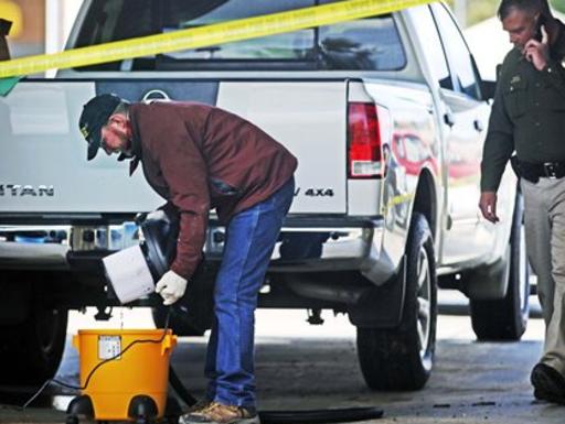 Park County Coroner Al Jenkins, left, looks through the contents of a vacuum filter at the Super Car Wash in Livingston Monday, Sept. 30, 2013 as part of an investigation into an early-morning hit and run on Interstate 90 in Sweet Grass County. Jenkins vacuumed water from a floor drain at the car wash - located near the corner of Park and south 11th Street - after someone reported finding a body part in the bay. State Trooper Bill Bullock, right, talks on his cell phone near a pickup truck that police said is not related to the investigation. A human body part found at a Livingston car wash Monday afternoon matches the victim of a fatal hit-and-run on Interstate 90 near Big Timber. Bullock told the Livingston Enterprise that the Sweet Grass County coroner determined the part came from the upper body of the man who was struck and killed Monday morning. (AP Photo/Livingston Enterprise, Shawn Raecke)