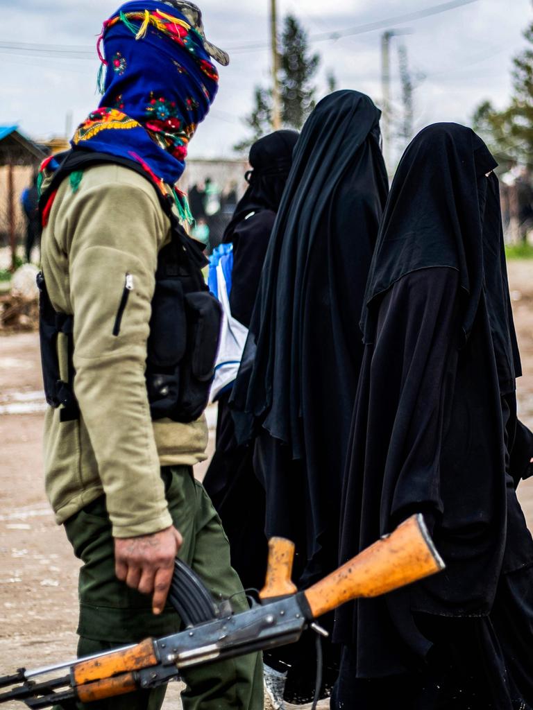 Foreign women, living in al-Hol camp, walk under the supervision of a fighter of the Syrian Democratic Forces (SDF). Picture: Delil Souleiman/AFP