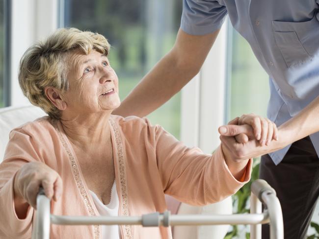 Old woman gets help with walking from a nurse