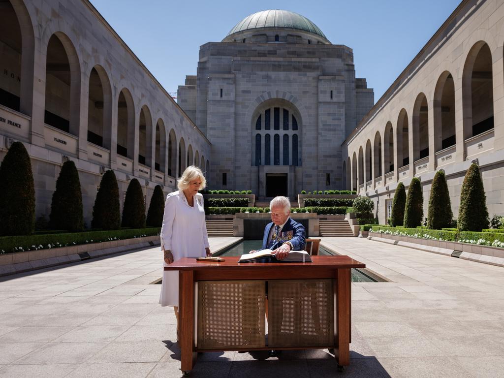 CKing Charles III signs a visitor's book as Queen Camilla stands next to him at the Australian War Memorial. Picture: Getty