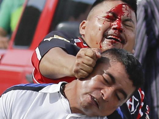 In this Tuesday, Sept. 16, 2014 photo, a man wearing a white shirt and holding onto to an air rifle fights with two other men as he tries to stop looters from storming into the Mega Supermarket in Los Cabos, Mexico. Enrique Galindo, national commissioner of the Federal Police, said on Thursday, seven people, two of whom were carrying firearms, were detained on suspicion of attempted looting. He said police would aggressively enforce the law. (AP Photo/Victor R. Caivano)