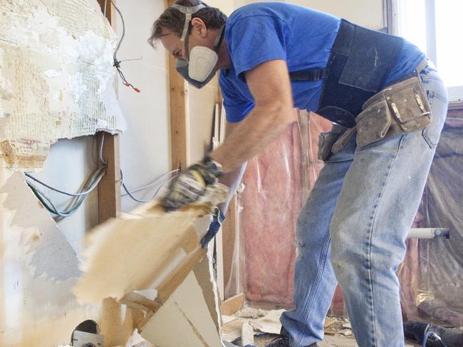 Man tearing out old kitchen during home renovations.