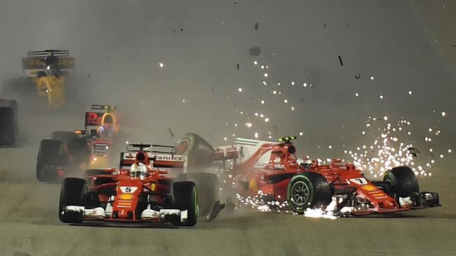 TOPSHOT - The car of Ferrari's Finnish driver Kimi Raikkonen (R) is seen after a crash as Ferrari's German driver Sebastian Vettel (C) leads during the Formula One Singapore Grand Prix in Singapore on September 17, 2017. / AFP PHOTO / MANAN VATSYAYANA