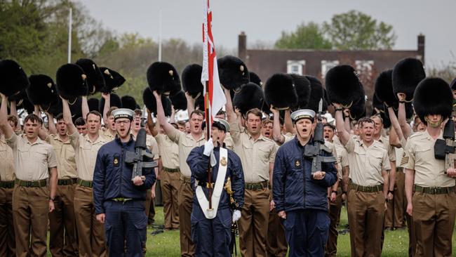 Soldiers from the Guards hold their bearskin hats in the air as they give three cheers for King Charles III and Queen Camilla as part of a Royal Salute in Odiham, England. Picture: Getty Images.