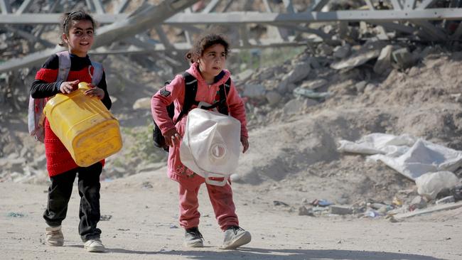 Palestinian girls carry empty jerry cans and their belongings in backpacks as they join people leaving the eastern sector of the Gaza Strip, following the resumption of Israeli airstrikes. Picture: Bashar Taleb/AFP