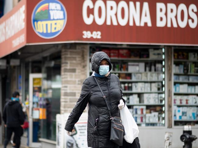 A woman wearing a mask walks pass a hardware store named 