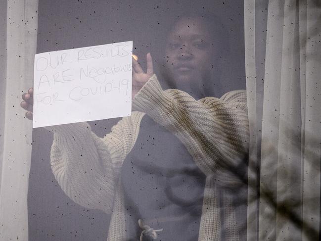 LONDON, ENGLAND - FEBRUARY 16: A woman holds up a sign reading "Our results are negative for COVID-19" from her room at the Radisson Blu, on February 16, 2021 in London, England. From yesterday, people arriving from 33 "red list" countries, including South Africa and the United Arab Emirates, must isolate in hotels rooms for 10 days at their own expense. The policy was announced late last month in response to the emergence of new variants of the novel coronavirus that are more resistant to existing vaccines. (Photo by Leon Neal/Getty Images) ***BESTPIX***