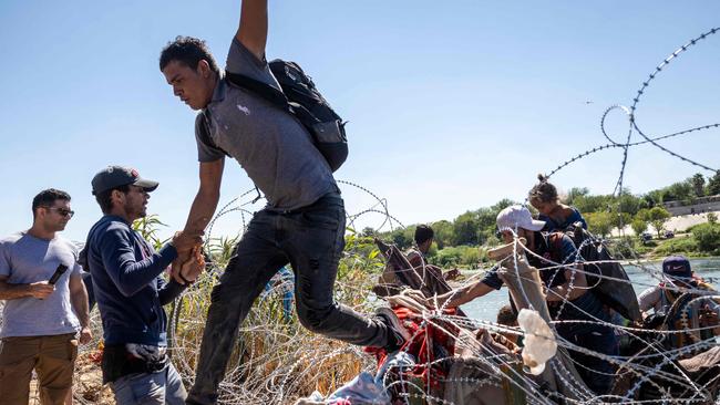 Immigrants cross over razor wire after crossing from Mexico into the United States at Eagle Pass, Texas. Picture: Getty Images/AFP