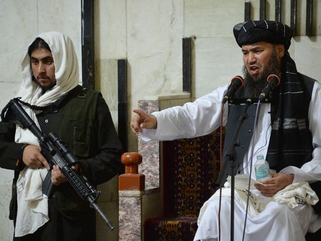 An armed Taliban fighter (L) stands next to Mullah, a religious leader, during prayers at the Pul-e Khishti Mosque in Kabul. Picture: AFP