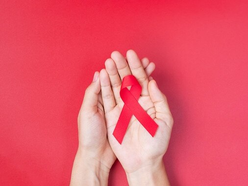 Hand holding Red Ribbon for supporting people living and illness. Healthcare and safe sex concept. December World Aids Day and multiple myeloma Cancer Awareness month