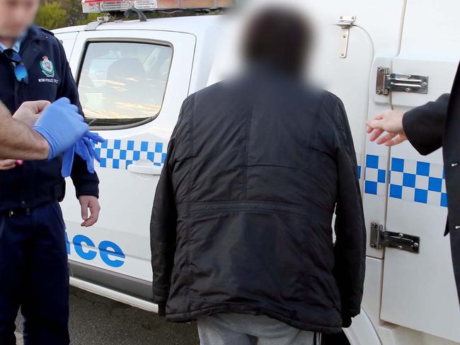 Police leading another of the men into a police vehicle