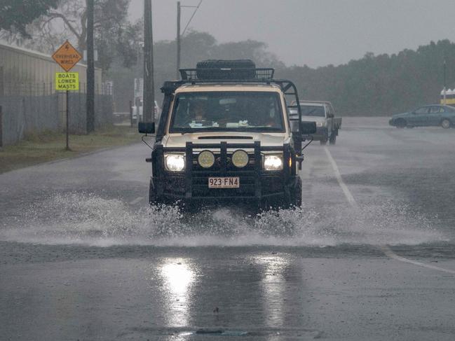 A motorist drives through floodwater as Cyclone Jasper approaches landfall in Cairns in far north Queensland on December 13, 2023. A tropical cyclone was building strength as it rolled towards northeastern Australia on 13 December, with authorities warning "life-threatening" floods could swamp coastal regions for days. (Photo by Brian CASSEY / AFP)