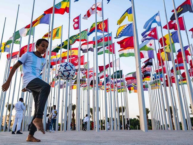 A boy plays with a ball at the Flag plaza in Doha on November 15, 2022, ahead of the Qatar 2022 World Cup football tournament. (Photo by ANDREJ ISAKOVIC / AFP)