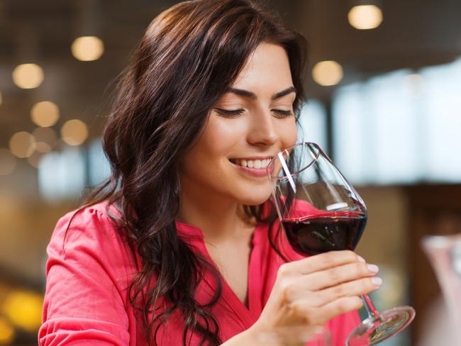 leisure, drinks, degustation, people and holidays concept - smiling woman drinking red wine at restaurant