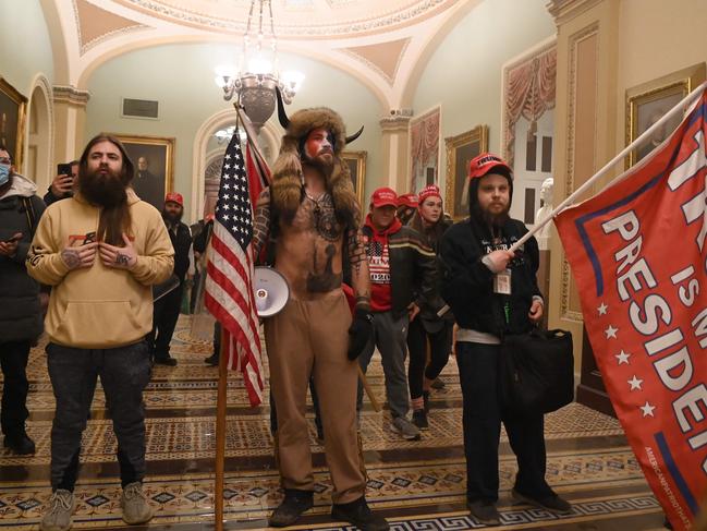 (FILES) In this file photo taken on January 06, 2021 supporters of US President Donald Trump, including member of the QAnon conspiracy group Jake Angeli, aka Yellowstone Wolf (C), enter the US Capitol in Washington, DC. - One year after supporters of Donald Trump stormed the US Capitol and shut down Congress, Americans still await a reckoning on the unprecedented challenge to the country's democracy. Was it a simple protest-turned-riot? An insurrection? A coup attempt plotted by Trump? Videos from January 6, 2021 bear witness to the violence wrought in the former president's name. Attackers beating security officers with iron bars and clubs. A policeman crushed in a doorway, howling in pain. Rioters clad in assault gear chanting "Hang Mike Pence," while the vice president and Democratic and Republican lawmakers flee. A woman shot to death in a Capitol hallway. Americans were stunned by the hours-long assault, and so was much of the world, accustomed to seeing the United States as a model of stable democracy. One year later, the brazen attempt to prevent Democrat Joe Biden from taking office after his victory in the November 2020 presidential election needs an accounting. (Photo by Saul LOEB / AFP)