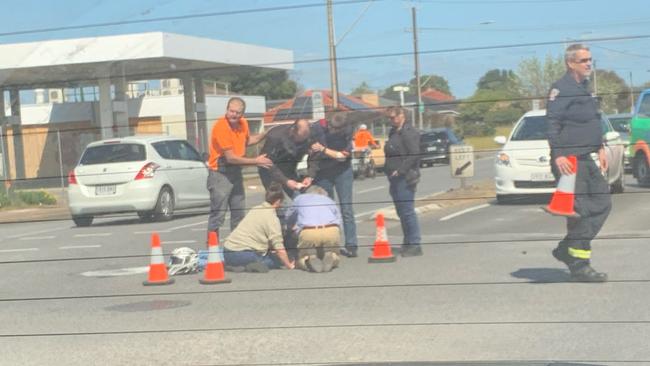 Bystanders rush to the aid of a ride at the intersection of Cross and Marion roads. Picture: Kitty Barr