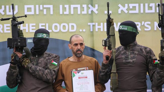 Hamas fighters escort Israeli hostage Or Levy on stage before handing him over to a Red Cross team in Deir el-Balah, central Gaza, on February 8. Picture: AFP