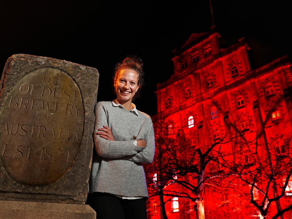 Cascade Brewery’s sales, events and tourism manager Lucy Fraser with the brewery’s main building lit up red for Dark Mofo. Picture: SAM ROSEWARNE