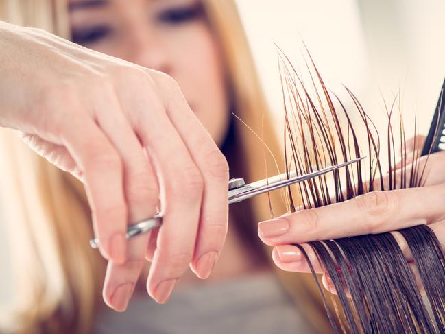 Close-up of a hairdresser cutting the hair of a woman. Selective focus.