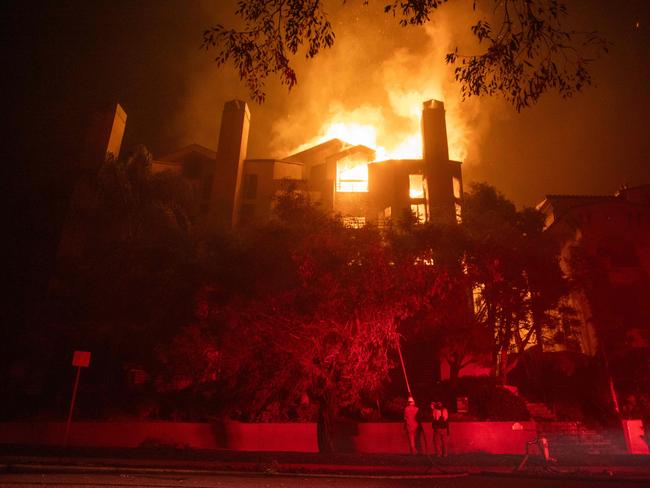 LOS ANGELES, CALIFORNIA - JANUARY 9: Flames from the Palisades Fire burn a residential building on Sunset Boulevard amid a powerful windstorm on January 9, 2025 in the Pacific Palisades neighborhood of Los Angeles, California. Multiple wildfires fueled by intense Santa Ana Winds are burning across Los Angeles County. At least five people have been killed, and over 25,000 acres have burned. Over 2,000 structures have also burned and almost 180,000 people are under orders to evacuate.   Apu Gomes/Getty Images/AFP (Photo by Apu Gomes / GETTY IMAGES NORTH AMERICA / Getty Images via AFP)