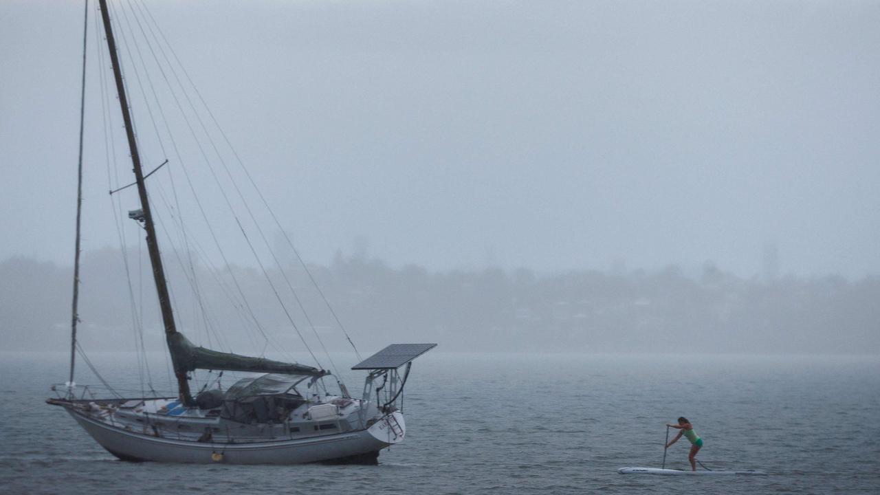 A woman paddles past a yacht at Wellington Point on Thursday. Picture: AFP