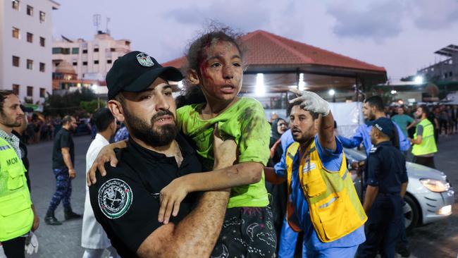 A member of the Palestinian security forces carries a child, wounded by Israeli air strikes, into Al-Shifa hospital in Gaza City. Photo: ABED / AFP