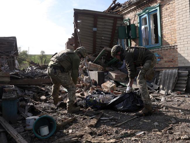 EDITORS NOTE: Graphic content / TOPSHOT - Ukrainian servicemen carry the body of a civilian from the rubbles of a destroyed house following shelling in Yakovlivka, Donetsk region on October 13, 2022, amid Russian invasion of Ukraine. (Photo by Anatolii Stepanov / AFP)