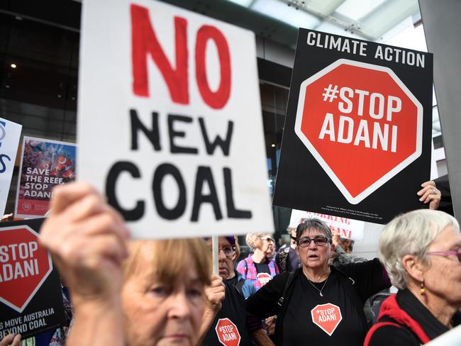 Anti-Adani protesters hold placards outside the offices of engineering and construction company GHD in Brisbane. Picture: AAP/Dan Peled