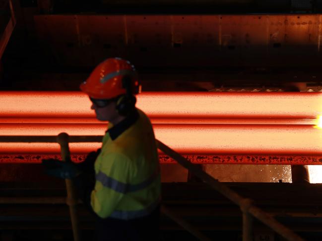 BUDGET2022: A worker watches as slabs of molten metal are cut to length at the Slabcaster at BlueScope Steel manufacturing plant in Port Kembla. John Feder